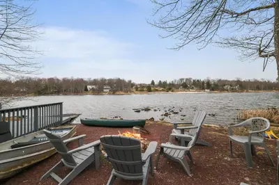 a group of chairs sitting next to a lake at Lakeside Escape Hot Tub Private Dock Ski in Tobyhanna