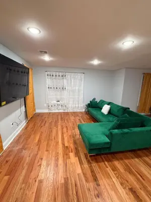 a living room with a green couch and wooden floors at The great homes in East Orange
