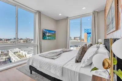 a bedroom with a large bed and large windows at Lux 2BD with KINGS - Pier Views - Near Fishtown! in Philadelphia