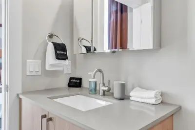 a white bathroom with a sink and a mirror at Lux 2BD with KINGS - Pier Views - Near Fishtown! in Philadelphia