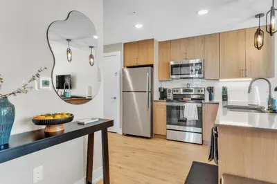 a kitchen with stainless steel appliances and wooden cabinets at Lux 2BD with KINGS - Pier Views - Near Fishtown! in Philadelphia
