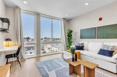 a living room with a white couch and a large window at Lux 2BD with KINGS - Pier Views - Near Fishtown! in Philadelphia