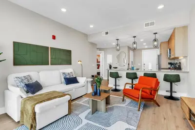 a living room with a white couch and a red chair at Lux 2BD with KINGS - Pier Views - Near Fishtown! in Philadelphia