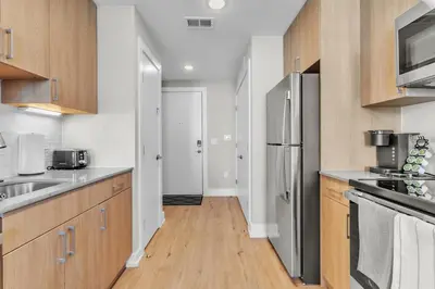 a kitchen with wooden cabinets and a stainless steel refrigerator at Luxe Studio with City Views - Near Fishtown in Philadelphia