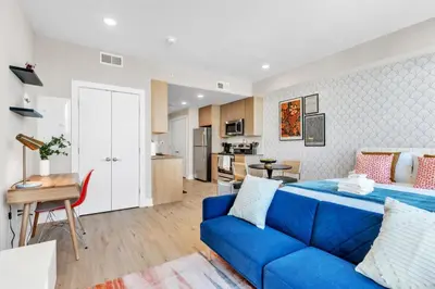 a living room with a blue couch and a kitchen at Scenic City Studio - Walkable - Smart TV in Philadelphia