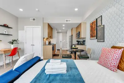 a bedroom with a blue and white bed and a kitchen at Scenic City Studio - Walkable - Smart TV in Philadelphia