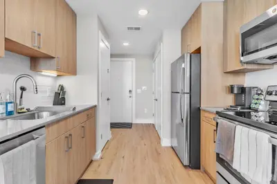 a kitchen with wooden cabinets and a stainless steel refrigerator at Scenic City Studio - Walkable - Smart TV in Philadelphia
