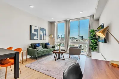 a living room with a green couch and a table at Serene 1BD Escape - Stunning City Views! in Philadelphia