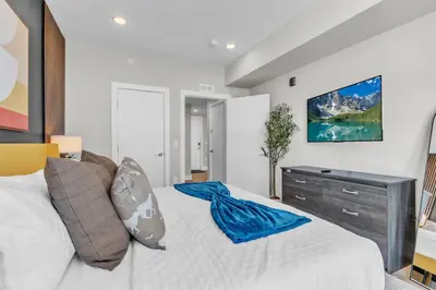 a bedroom with a large white bed with a dresser at Serene 1BD Escape - Stunning City Views! in Philadelphia