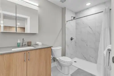 a white bathroom with a toilet and a shower at Serene 1BD Escape - Stunning City Views! in Philadelphia
