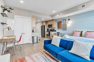 a living room with a blue couch and a kitchen at Waterfront Studio - Steps from Fishtown and Old City in Philadelphia