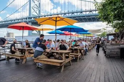 a group of people sitting at tables with umbrellas at Waterfront Studio - Steps from Fishtown and Old City in Philadelphia