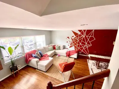 a person sitting on a couch in a living room at Easy PATH&Bus access- NYC| designer home + Deck. in Jersey City