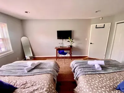 two beds in a bedroom with a desk and a tv at Easy PATH&Bus access- NYC| designer home + Deck. in Jersey City