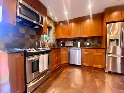a kitchen with wooden cabinets and stainless steel appliances at Easy PATH&Bus access- NYC| designer home + Deck. in Jersey City