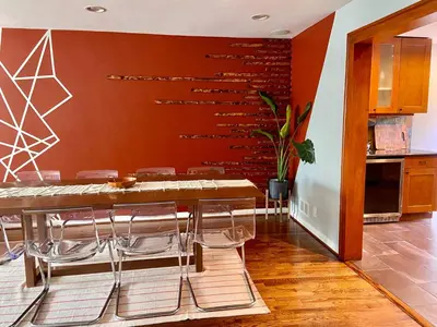 a dining room with a wooden table and chairs at Easy PATH&Bus access- NYC| designer home + Deck. in Jersey City