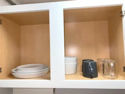 a white cabinet with plates and other kitchen utensils at Chelsea Studio-Shared Bathroom with Kitchen Twin Bunk Bed in New York