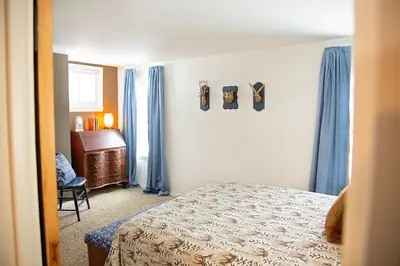 a bedroom with a bed and a desk and blue curtains at The Farmhouse at Deer Run