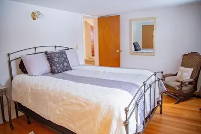 a bed in a bedroom with a mirror and a chair at The Farmhouse at Deer Run