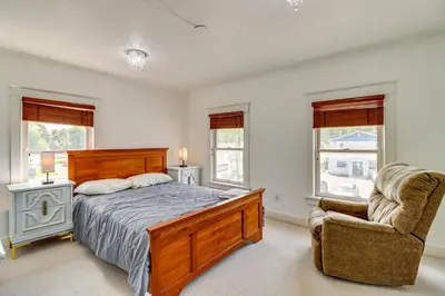 a bedroom with a bed and a chair and windows at Walkable Abode in Stroudsburgs Business District! in Stroudsburg