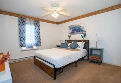 a bedroom with a bed and a ceiling fan at Joy Cabin Where Family Friends Make Memories in Long Pond