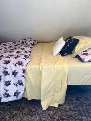 a bed with two pillows on top of it at Atic Apartment in Perth Amboy