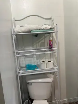 a bathroom with a toilet and towels on a shelf at Atic Apartment in Perth Amboy