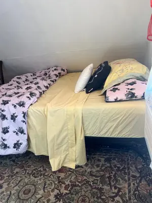 a bed with pillows on it in a room at Atic Apartment in Perth Amboy
