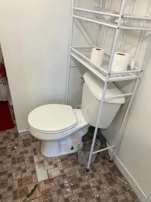 a bathroom with a toilet and a shelf with toilet paper at Atic Apartment in Perth Amboy