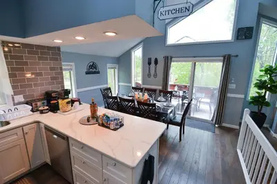 a kitchen and dining room with blue walls and a table at Bool Bear Lodge a pet friendly Pocono Vacation Home with Fireplace, BBQ and more in Tobyhanna