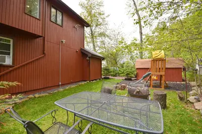 a table and chairs in a yard next to a house at Bool Bear Lodge a pet friendly Pocono Vacation Home with Fireplace, BBQ and more in Tobyhanna