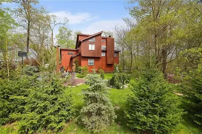 a house in the middle of a yard with trees at Bool Bear Lodge a pet friendly Pocono Vacation Home with Fireplace, BBQ and more in Tobyhanna
