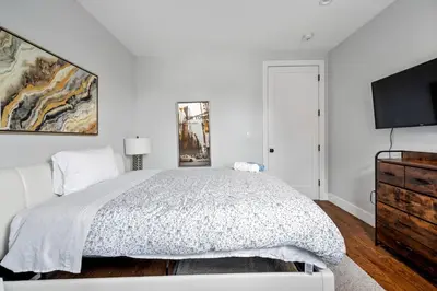 a white bedroom with a bed and a flat screen tv at 2 Queen Beds, TV's in Bedroom, Path to Manhattan in Jersey City