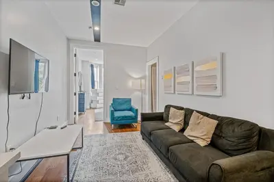 a living room with a brown couch and a blue chair at 2 Queen Beds, TV's in Bedroom, Path to Manhattan in Jersey City