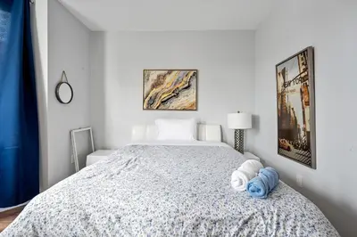 a white bedroom with a bed with towels on it at 2 Queen Beds, TV's in Bedroom, Path to Manhattan in Jersey City