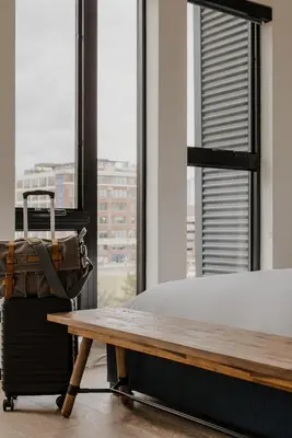 a bed and a suitcase in a room with a window at Sosuite at The Onyx - Museum District in Philadelphia