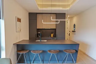a kitchen with a blue island with stools at Sosuite at The Onyx - Museum District in Philadelphia