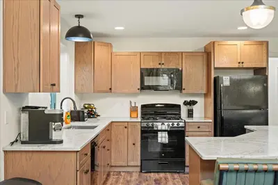 a kitchen with wooden cabinets and a black refrigerator at 5 Br Sleeps 14 Hot Tub-Sauna-Movie Theatre-Arcade in Albrightsville