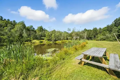 a picnic table in a field next to a pond at Harmony House in Liberty