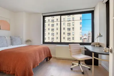 a bedroom with a bed and a desk and a window at Blueground Chelsea rooftop nr The High Line NYC-1201 in New York