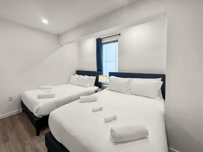 two beds in a room with white walls and a window at Apartmint at Fishtown Flats - Philadelphia in Philadelphia
