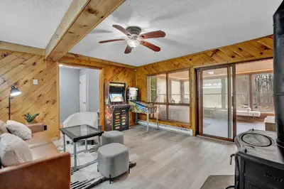 a living room with wooden walls and a ceiling fan at Pocono Blue with Paddleboards, Spa, Indoor Jacuzzi, GameRoom, Lake, EV in Gouldsboro