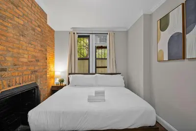 a white bed in a room with a brick wall at Stylish Escape in the East Village in New York