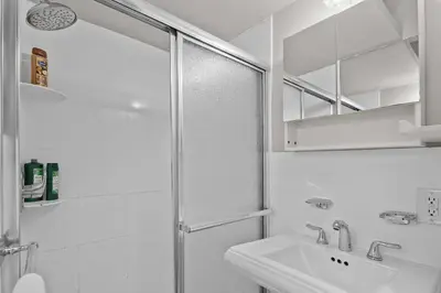 a white bathroom with a shower and a sink at Stylish Escape in the East Village in New York