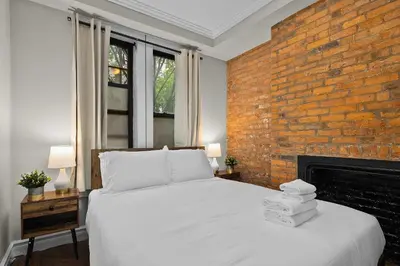 a bedroom with a white bed and a brick wall at Stylish Escape in the East Village in New York