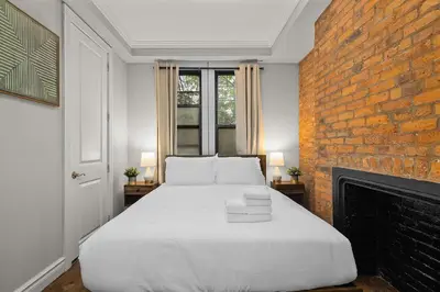a bedroom with a white bed and a brick wall at Stylish Escape in the East Village in New York
