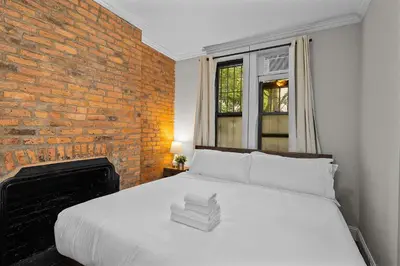 a bedroom with a white bed with a brick wall at Stylish Escape in the East Village in New York