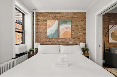a white bed in a room with a brick wall at Chic NYC Escape in Vibrant Downtown in New York