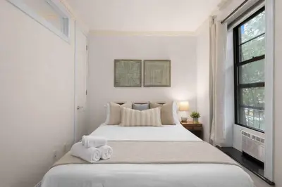 a white bedroom with a bed with towels on it at Stylish East Side Escape Steps from Fun in New York