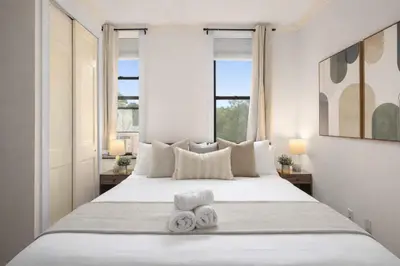 a bedroom with a large white bed with two towels at Stylish East Side Escape Steps from Fun in New York